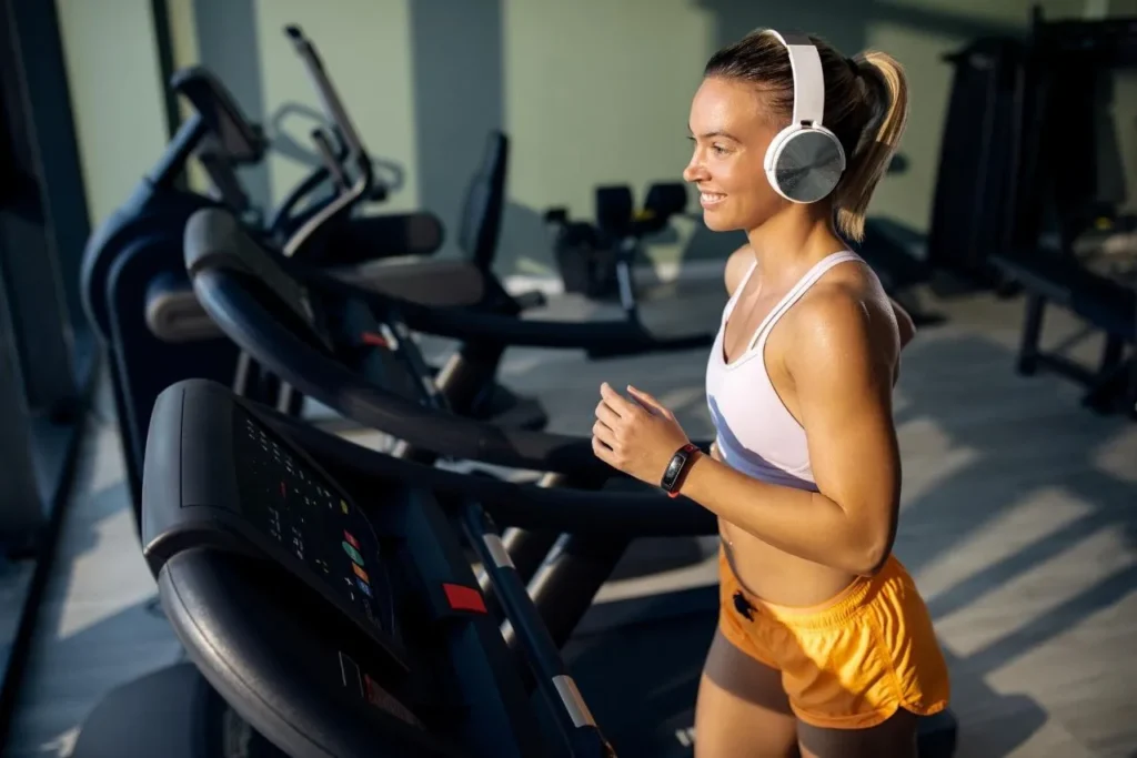 A young woman exercising on a treadmill or cycling machine in a gym, focused on her workout.
