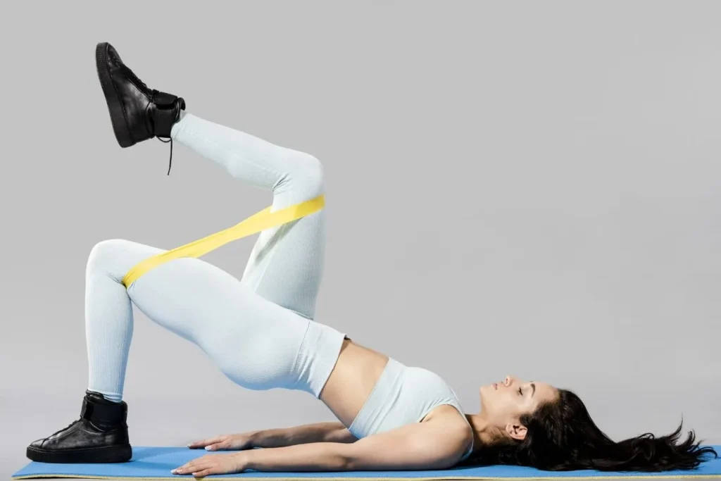 A fit young woman performing an intense workout using resistance bands, engaging her core and leg muscles.