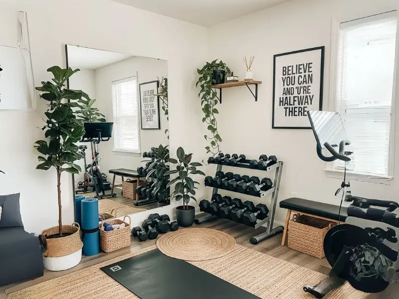 home gym with a serene atmosphere, decorated with a large mirror, a motivational quote poster, and several indoor plants.